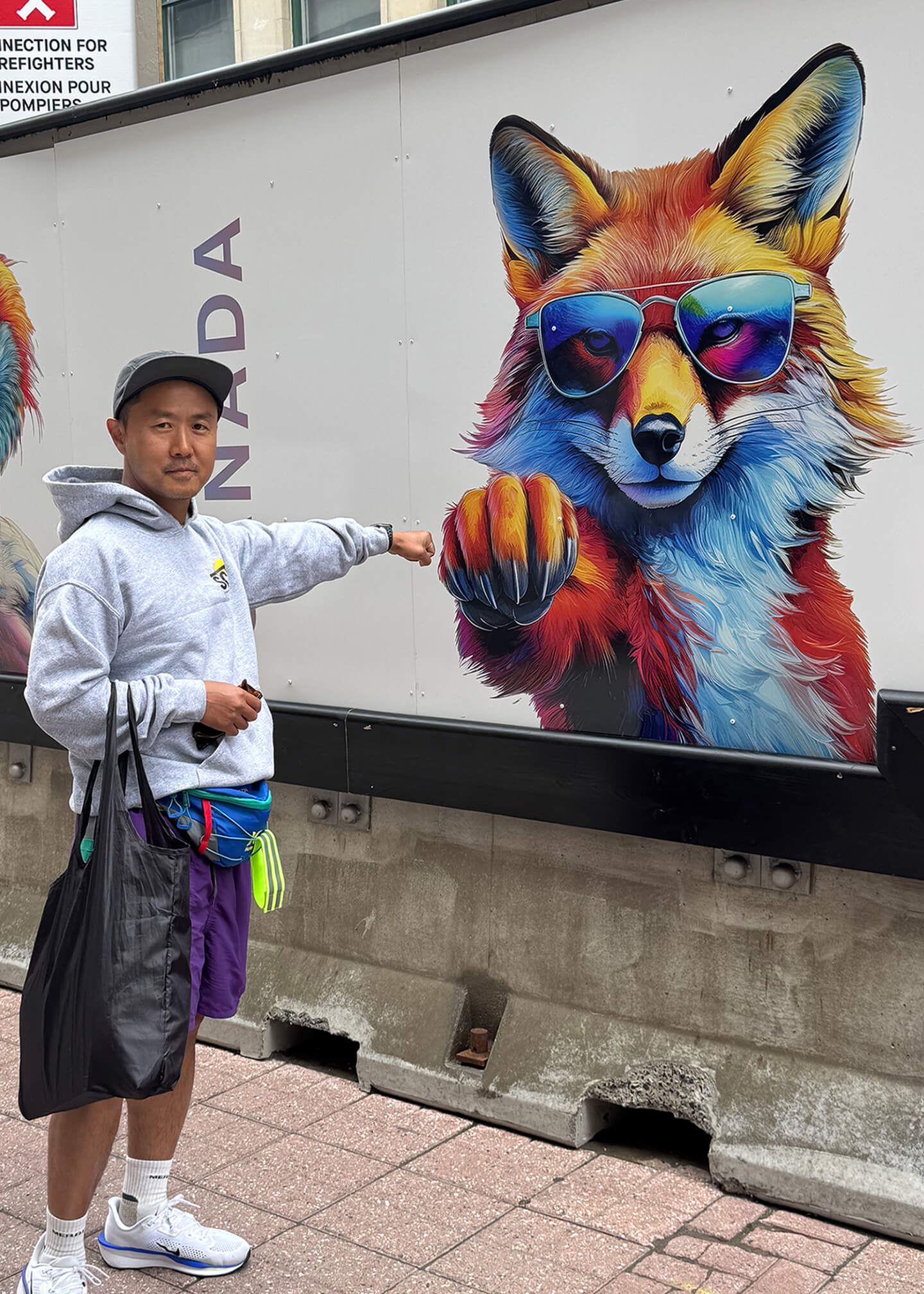 Posing for a photo in front of a billobard with cartoon fox giving a fist-bump.